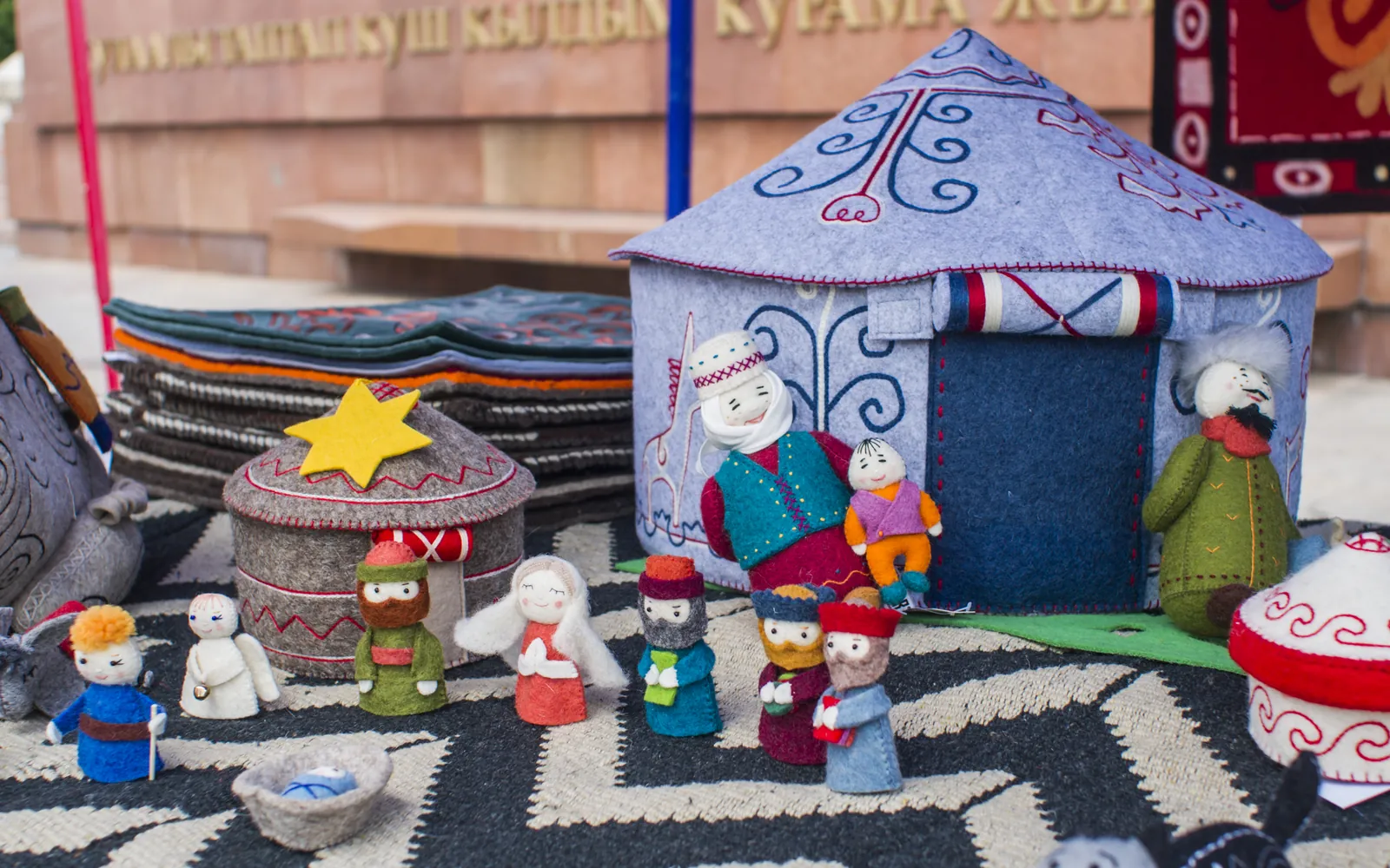 A display of colourful handmade felt toys, including small figures and a felt house