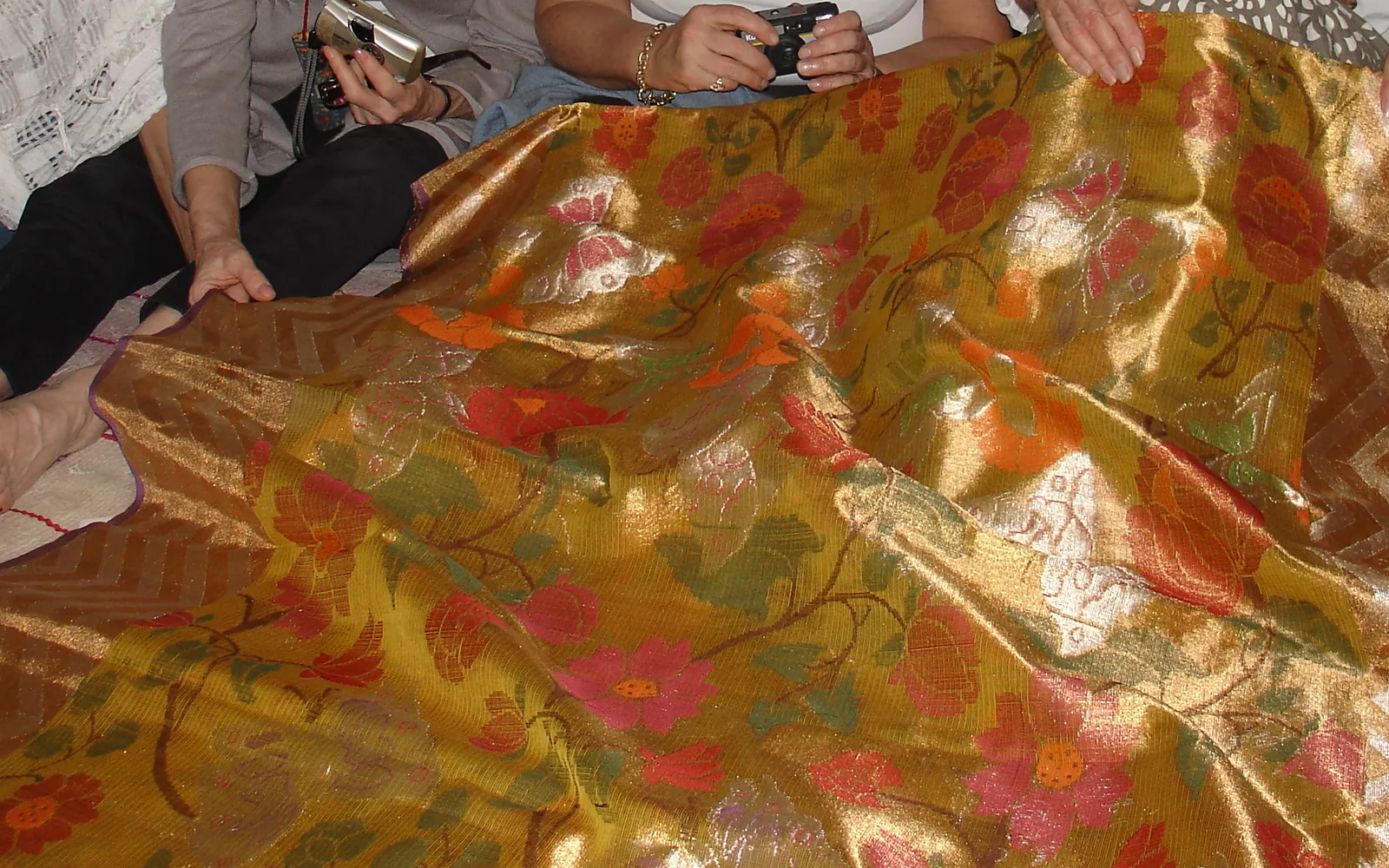 A handwoven Kota Doria piece with gold zari and a floral pattern spread out for viewing